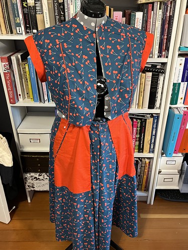 Half-finished dress in teal cotton with red cherries, with red pockets and shoulder bands